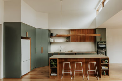 Mid-sized country open plan kitchen in Melbourne with a double-bowl sink, green cabinets, white splashback, porcelain splashback, black appliances, with island and vaulted.