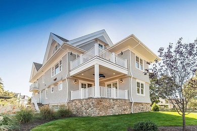 Large beach style gray three-story wood gable roof photo in New York