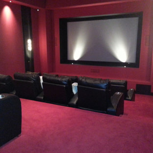 Aménagement d'une salle de cinéma classique ouverte avec moquette, un écran de projection, un mur rose et un sol rose.