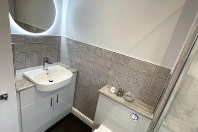 Medium sized family bathroom in Other with flat-panel cabinets, grey cabinets, a walk-in shower, a one-piece toilet, grey tiles, porcelain tiles, white walls, a built-in sink, laminate worktops, black floors, an open shower, multi-coloured worktops, a single sink and a built in vanity unit.