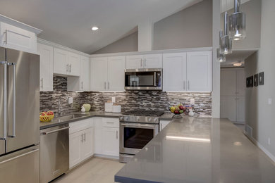 Example of a mid-sized transitional u-shaped light wood floor open concept kitchen design in San Francisco with an undermount sink, white cabinets, quartz countertops, multicolored backsplash, metal backsplash, stainless steel appliances, a peninsula and shaker cabinets
