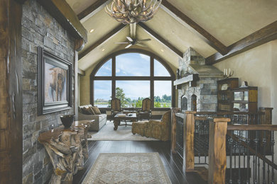 Living room - large rustic open concept dark wood floor living room idea in Other with beige walls, a standard fireplace, a stone fireplace and no tv