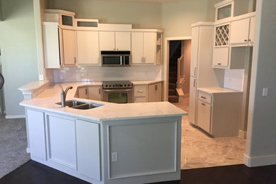 Example of a transitional porcelain tile kitchen design in Oklahoma City with a double-bowl sink, flat-panel cabinets, gray cabinets, quartz countertops, white backsplash, subway tile backsplash and stainless steel appliances