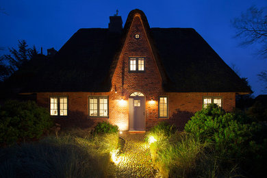 Großes, Zweistöckiges Landhausstil Einfamilienhaus mit Backsteinfassade, roter Fassadenfarbe und Halbwalmdach in Sonstige