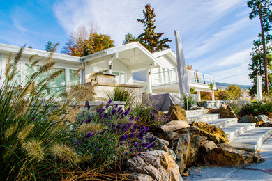 Large beach style two-storey white exterior in Vancouver with concrete fiberboard siding and a clipped gable roof.