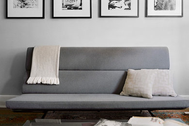 Example of a mid-sized minimalist enclosed dark wood floor living room design in New York with white walls, no fireplace and a wall-mounted tv