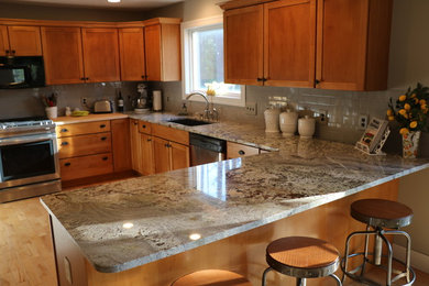 Eat-in kitchen - mid-sized contemporary u-shaped eat-in kitchen idea in Grand Rapids with an undermount sink, shaker cabinets, medium tone wood cabinets, granite countertops, gray backsplash, subway tile backsplash, stainless steel appliances, a peninsula and gray countertops