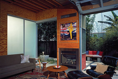 Small beach style concrete floor living room photo in Los Angeles with a tv stand, a two-sided fireplace and a metal fireplace
