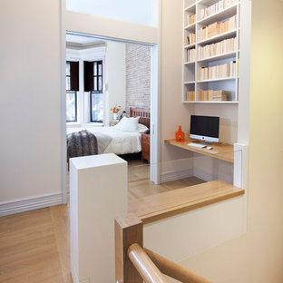 Photo of a large contemporary study room in New York with yellow walls, light hardwood floors and a built-in desk.