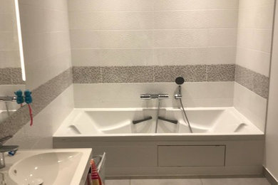 Cette image montre une petite salle d'eau design avec une baignoire encastrée, un carrelage gris, mosaïque, un mur gris, carreaux de ciment au sol, une grande vasque et un sol gris.