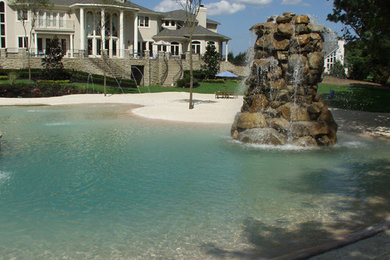 Huge island style backyard custom-shaped pool fountain photo in New York