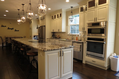 Kitchen - large transitional galley dark wood floor and brown floor kitchen idea with a double-bowl sink, raised-panel cabinets, white cabinets, granite countertops, white backsplash, porcelain backsplash, stainless steel appliances and an island