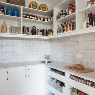 Large farmhouse kitchen pantry ideas - Large farmhouse l-shaped light wood floor kitchen pantry photo in Melbourne with white cabinets, white backsplash, subway tile backsplash, a drop-in sink, beaded inset cabinets, solid surface countertops, stainless steel appliances and an island
