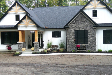 Imagen de fachada de casa blanca y negra de estilo americano grande de una planta con revestimiento de vinilo, tejado a dos aguas, tejado de teja de madera y panel y listón