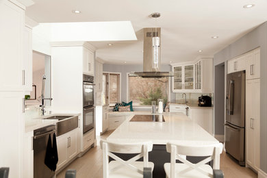 Inspiration for a transitional galley light wood floor and beige floor eat-in kitchen remodel in Toronto with a farmhouse sink, shaker cabinets, white cabinets, stainless steel appliances, an island, quartz countertops and ceramic backsplash