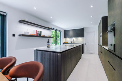 This is an example of a medium sized modern galley kitchen/diner in Manchester with an integrated sink, stainless steel appliances and an island.