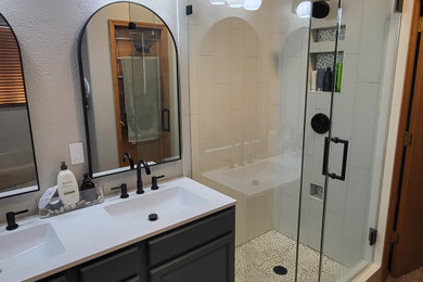 Mid-sized minimalist gray tile and porcelain tile laminate floor, beige floor and double-sink corner shower photo in Denver with shaker cabinets, blue cabinets, a hot tub, gray walls, an integrated sink, quartzite countertops, a hinged shower door, white countertops, a niche and a built-in vanity