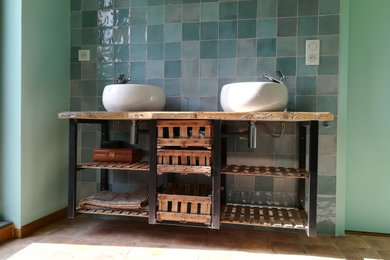 Idées déco pour une grande salle de bain principale industrielle en bois vieilli avec un placard sans porte, un carrelage vert, des carreaux en terre cuite, un mur vert, tomettes au sol, un lavabo posé, un plan de toilette en bois, un sol marron, meuble double vasque et meuble-lavabo suspendu.