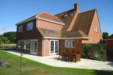 Стильный дизайн: двухэтажный, кирпичный частный загородный дом среднего размера с двускатной крышей, черепичной крышей и красной крышей - последний тренд