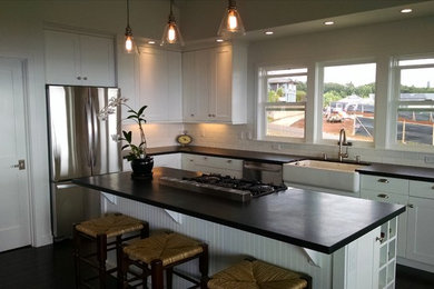 Contemporary kitchen in Hawaii with a farmhouse sink, shaker cabinets, white cabinets, subway tile splashback, stainless steel appliances and with island.