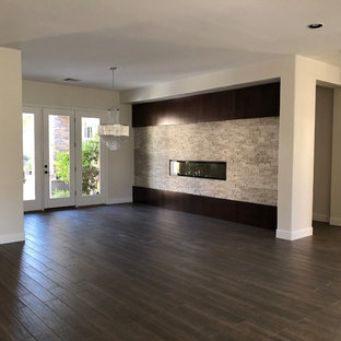 ラスベガスの広いコンテンポラリースタイルのLDKの画像 (グレーの壁、磁器タイルの床、横長型暖炉、石材の暖炉まわり、茶色い床)