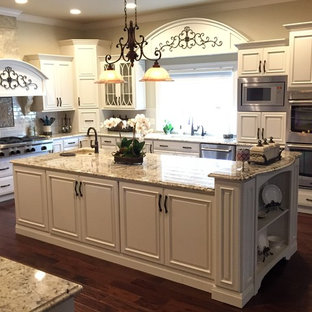 Réalisation d'une très grande arrière-cuisine victorienne en U avec un évier encastré, un placard avec porte à panneau surélevé, des portes de placard blanches, un plan de travail en granite, une crédence blanche, un électroménager en acier inoxydable et 2 îlots.