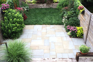 This is an example of a small modern backyard full sun driveway for fall in New York with natural stone pavers and a container garden.