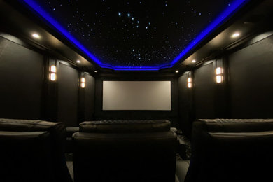 На фото: изолированный домашний кинотеатр среднего размера в современном стиле с проектором и черными стенами с