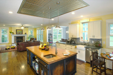 Inspiration for a large timeless u-shaped medium tone wood floor eat-in kitchen remodel in Cleveland with a farmhouse sink, raised-panel cabinets, white cabinets, solid surface countertops, gray backsplash, subway tile backsplash, stainless steel appliances and an island