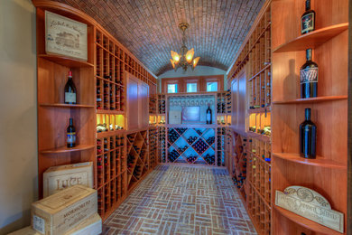 Inspiration for a traditional wine cellar in Austin with brick floors, display racks and red floor.