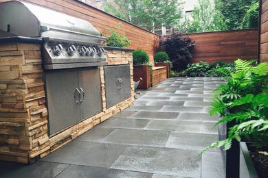 Photo of a mid-sized arts and crafts side yard patio in New York with an outdoor kitchen, concrete pavers and no cover.
