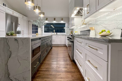 Huge u-shaped medium tone wood floor, brown floor and vaulted ceiling enclosed kitchen photo in Dallas with an undermount sink, shaker cabinets, white cabinets, quartzite countertops, gray backsplash, stone slab backsplash, stainless steel appliances, an island and gray countertops