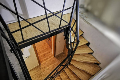 Ejemplo de escalera en L urbana de tamaño medio con escalones de madera, contrahuellas de madera y barandilla de metal