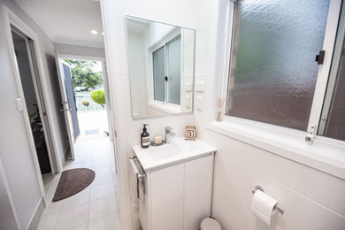 Photo of a modern bathroom in Sydney with white cabinets, a corner shower, white tile, a sliding shower screen, white benchtops, a niche, a single vanity and a freestanding vanity.