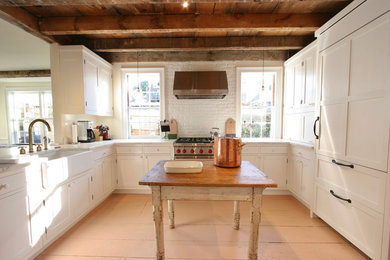 Inspiration for a large rustic u-shaped orange floor eat-in kitchen remodel in Boston with a farmhouse sink, shaker cabinets, white cabinets, white backsplash, brick backsplash, stainless steel appliances and an island