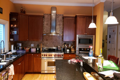 Example of a mid-sized minimalist l-shaped light wood floor open concept kitchen design in Chicago with a double-bowl sink, shaker cabinets, white cabinets, quartzite countertops, white backsplash, ceramic backsplash, stainless steel appliances, an island and black countertops