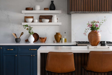 Example of a mid-sized transitional l-shaped medium tone wood floor and beige floor eat-in kitchen design in Toronto with a farmhouse sink, shaker cabinets, blue cabinets, quartz countertops, white backsplash, quartz backsplash, stainless steel appliances, an island and white countertops