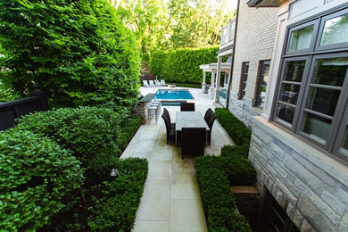 Large contemporary backyard partial sun garden in Toronto with a fire feature and natural stone pavers for summer.