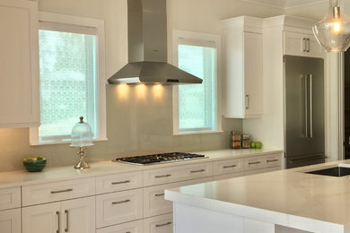Contemporary kitchen in Other with white cabinets, beige splashback, glass sheet splashback, light hardwood floors, with island and beige floor.