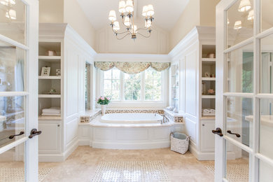 Photo of an expansive traditional master bathroom in San Diego with furniture-like cabinets, white cabinets, a drop-in tub, a double shower, a one-piece toilet, beige tile, travertine, beige walls, travertine floors, an undermount sink and marble benchtops.