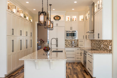 Photo of a mid-sized transitional galley kitchen pantry in Dallas with an undermount sink, shaker cabinets, white cabinets, granite benchtops, beige splashback, ceramic splashback, stainless steel appliances, light hardwood floors and with island.