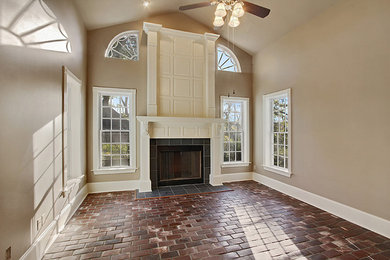 Example of a mid-sized classic red floor family room design in New Orleans with brown walls, a standard fireplace, a tile fireplace and no tv