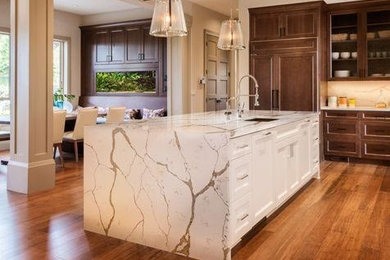 Eat-in kitchen - transitional medium tone wood floor eat-in kitchen idea in Edmonton with a single-bowl sink, recessed-panel cabinets, dark wood cabinets, solid surface countertops, white backsplash, stone slab backsplash, stainless steel appliances and an island