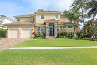 Inspiration for a large contemporary yellow two-story stucco exterior home remodel in Miami with a hip roof