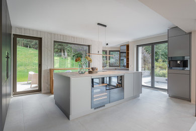 Diseño de cocina contemporánea extra grande abierta con fregadero bajoencimera, armarios con paneles lisos, puertas de armario grises y una isla