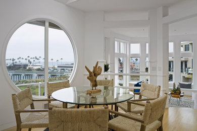 Ispirazione per una sala da pranzo aperta verso il soggiorno stile marinaro di medie dimensioni con pareti bianche, parquet chiaro e pavimento beige