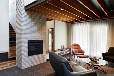 This is an example of a mid-sized modern formal enclosed living room in Canberra - Queanbeyan with white walls, ceramic floors, a standard fireplace, a brick fireplace surround, no tv and black floor.
