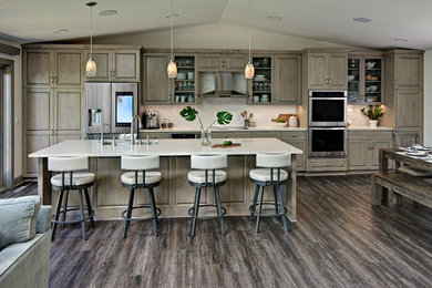 Example of a mid-sized transitional l-shaped dark wood floor and brown floor open concept kitchen design in Minneapolis with an undermount sink, raised-panel cabinets, medium tone wood cabinets, solid surface countertops, white backsplash, subway tile backsplash, stainless steel appliances, an island and white countertops