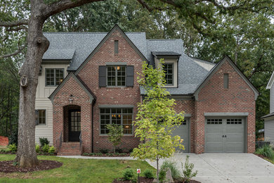 This is an example of a transitional two-storey brick red exterior in Raleigh with a shingle roof.