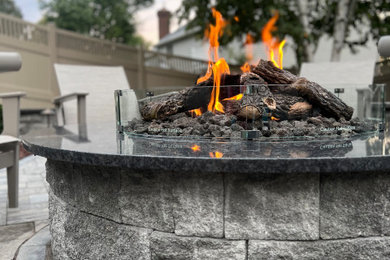Mid-sized backyard stone patio photo in New York with a fire pit and no cover